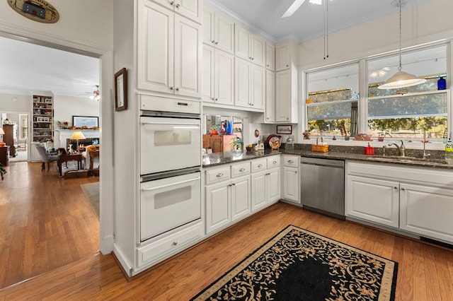 kitchen featuring ceiling fan, stainless steel dishwasher, a sink, and white cabinetry