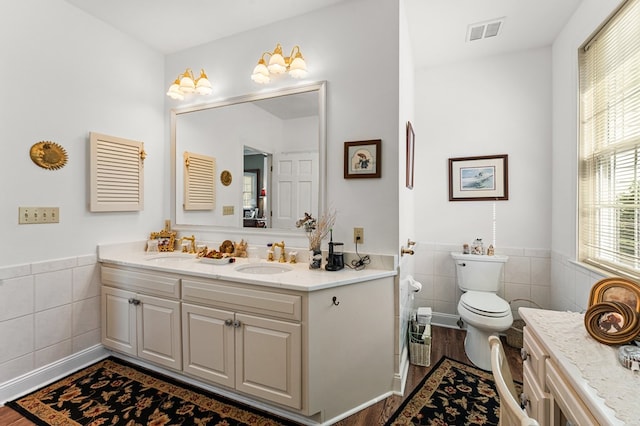 bathroom with visible vents, a sink, tile walls, and toilet