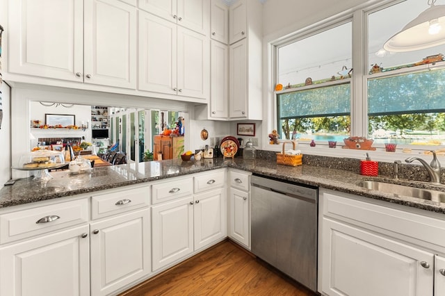 kitchen with dark stone counters, white cabinets, sink, stainless steel dishwasher, and light hardwood / wood-style floors