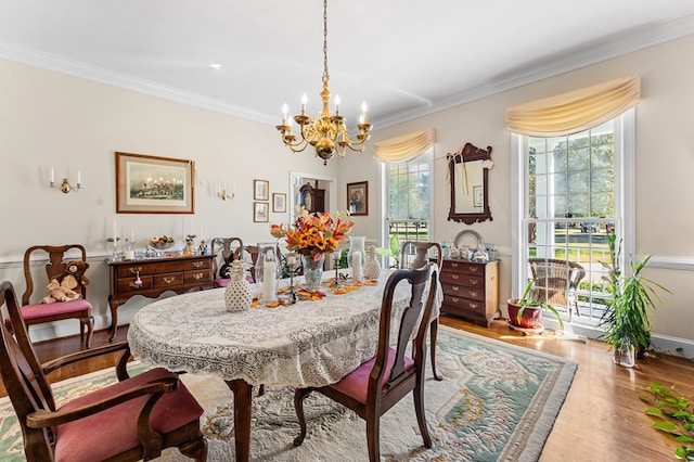 dining area with a chandelier, crown molding, and wood finished floors