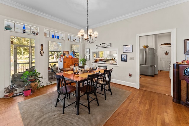 dining area with ornamental molding, a chandelier, baseboards, and wood finished floors