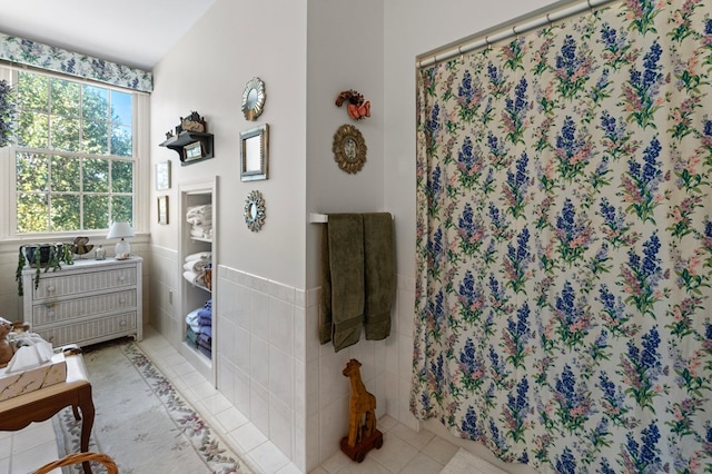 full bath with a wainscoted wall, tile walls, curtained shower, vanity, and tile patterned floors