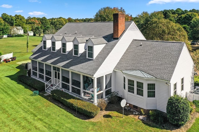 rear view of house featuring a lawn and a sunroom