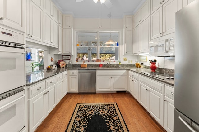 kitchen featuring stainless steel appliances, a sink, white cabinets, and light wood-style floors