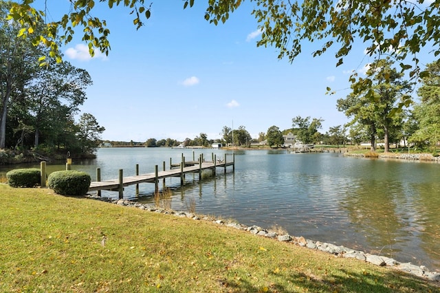 view of dock with a lawn and a water view