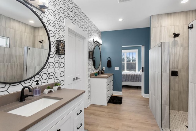 bathroom featuring hardwood / wood-style floors, vanity, and a tile shower