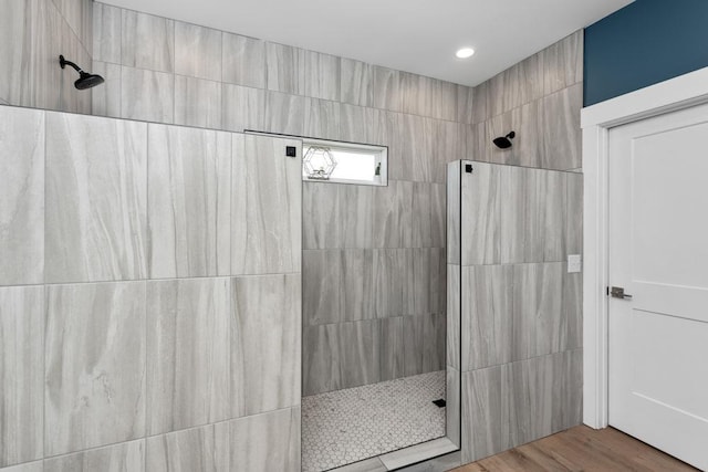 bathroom featuring wood-type flooring and a tile shower