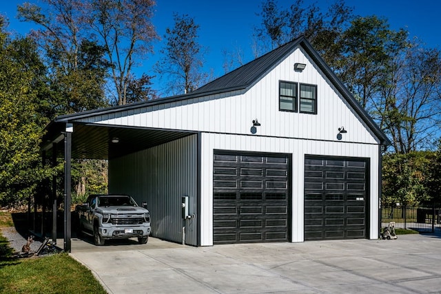 garage featuring a detached garage, fence, and concrete driveway
