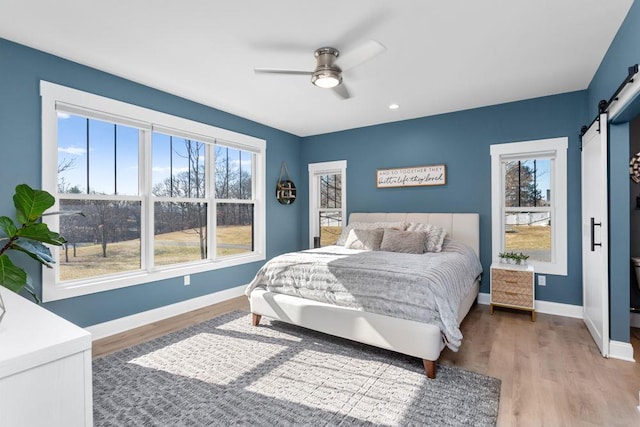 bedroom featuring ceiling fan, wood-type flooring, and a barn door