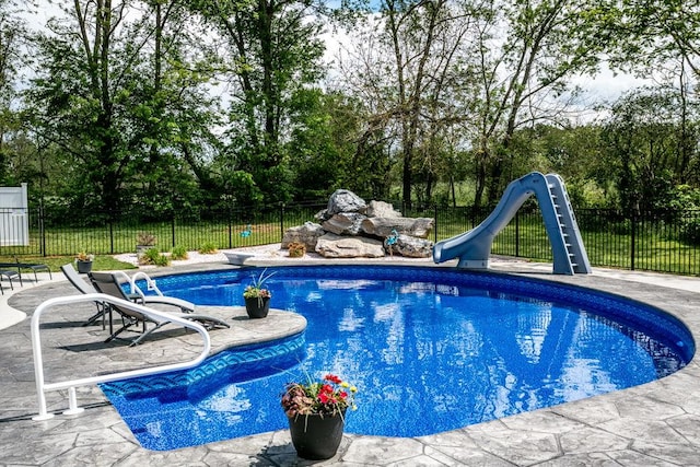 view of pool featuring a water slide, a diving board, a patio, and fence