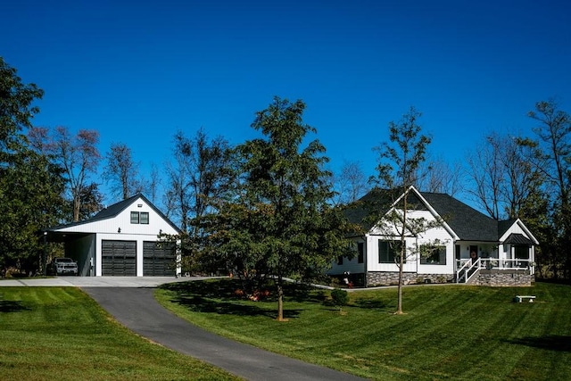 view of front facade featuring a garage, a front yard, an outbuilding, and asphalt driveway