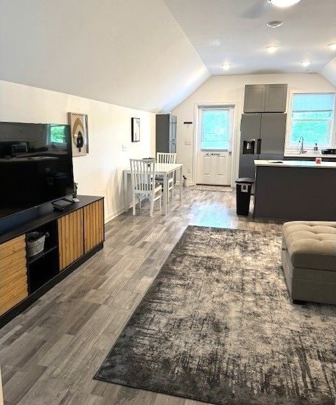 living area with lofted ceiling, wood finished floors, healthy amount of natural light, and baseboards