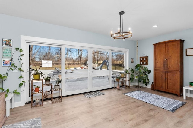 doorway with a chandelier, light wood finished floors, recessed lighting, and baseboards