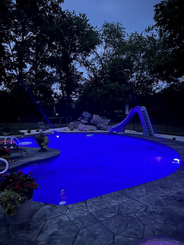 view of swimming pool with a water slide, a fenced backyard, and a patio area