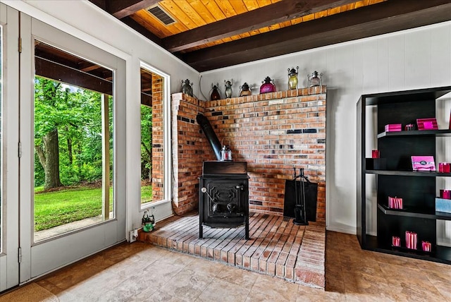 living room featuring a wood stove, beamed ceiling, and wood ceiling