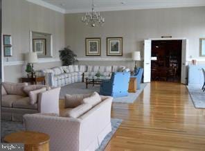 living room featuring crown molding, hardwood / wood-style flooring, and an inviting chandelier