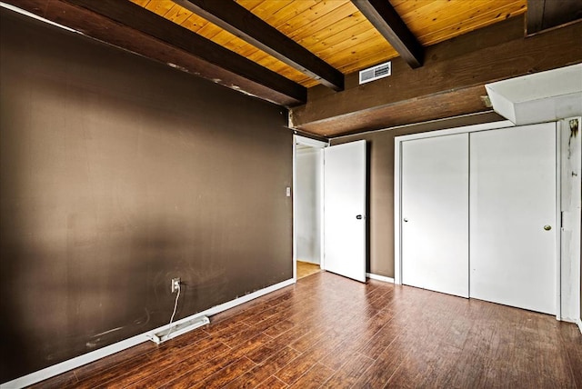 unfurnished bedroom with a closet, dark wood-type flooring, beamed ceiling, and wooden ceiling