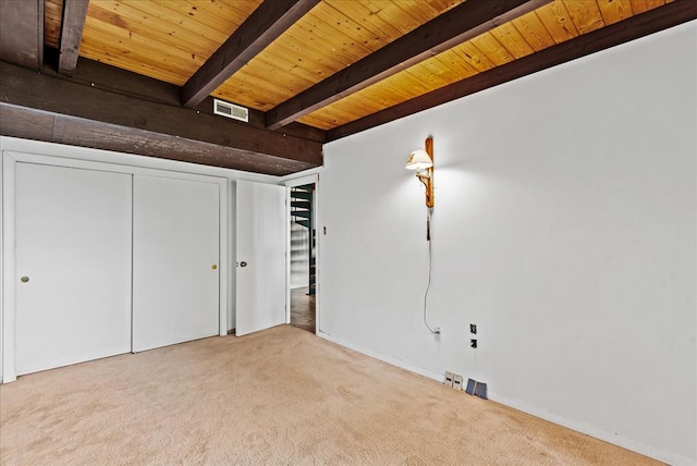 unfurnished bedroom with beamed ceiling, light colored carpet, wooden ceiling, and a closet