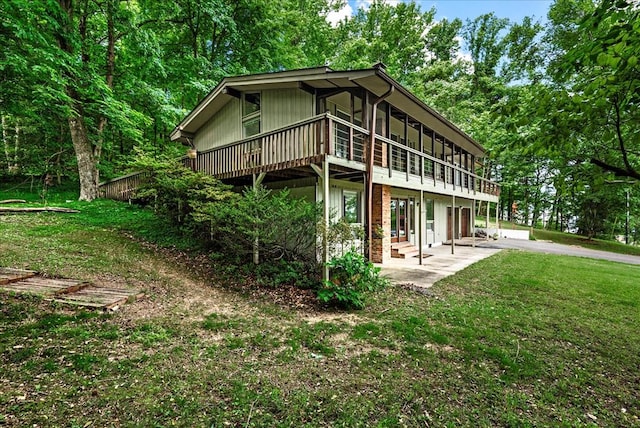 rear view of house with a patio, a sunroom, and a lawn