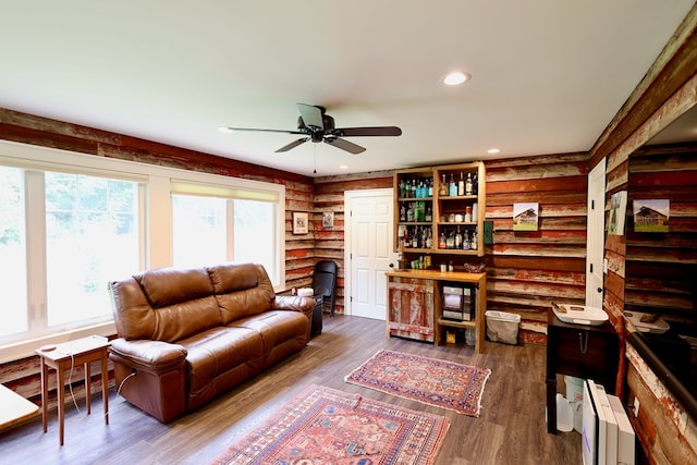 living room with ceiling fan, dark hardwood / wood-style flooring, and log walls