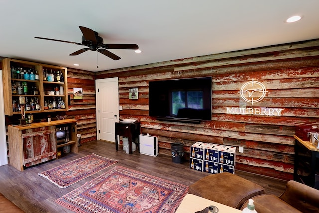 living room featuring ceiling fan, dark wood-type flooring, and log walls