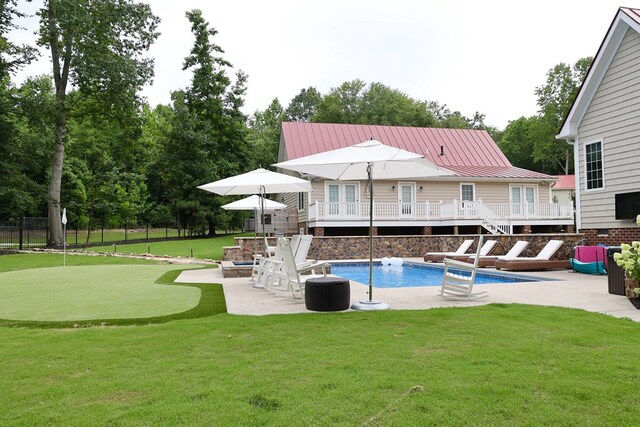 view of swimming pool featuring a wooden deck, a yard, and a patio