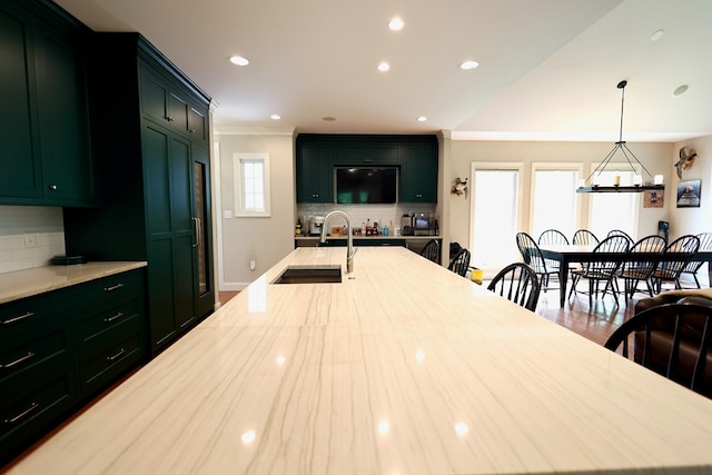 kitchen with sink, green cabinets, crown molding, decorative light fixtures, and decorative backsplash