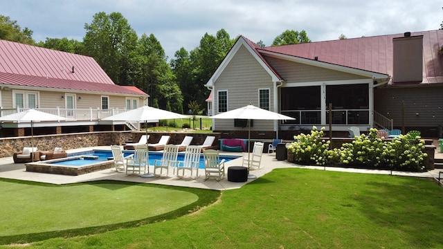 rear view of house with a patio, a lawn, and a pool with hot tub