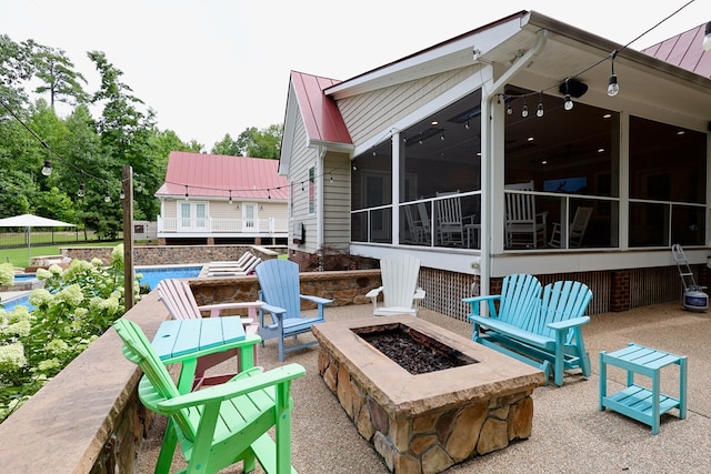 view of patio / terrace with a swimming pool, a fire pit, and a sunroom