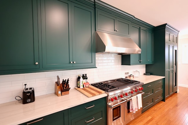 kitchen featuring decorative backsplash, light hardwood / wood-style floors, double oven range, and green cabinetry