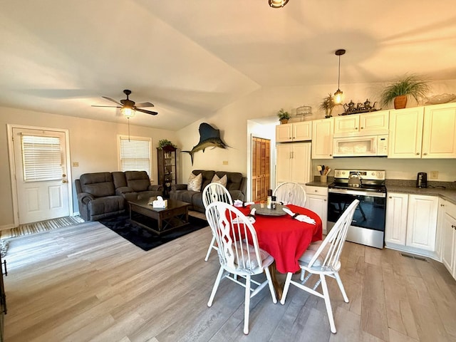 dining space featuring ceiling fan, vaulted ceiling, and light hardwood / wood-style floors