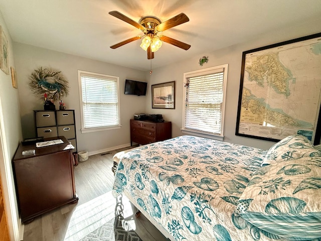 bedroom featuring ceiling fan, multiple windows, and light wood-type flooring