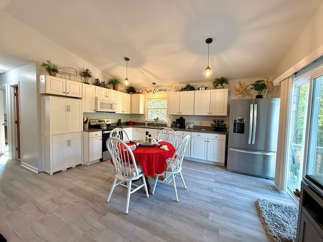 kitchen featuring lofted ceiling, stainless steel appliances, hanging light fixtures, and light wood-type flooring