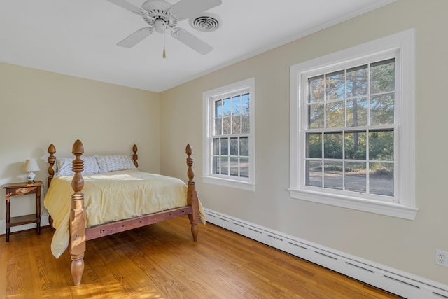 bedroom with wood-type flooring, a baseboard radiator, and ceiling fan