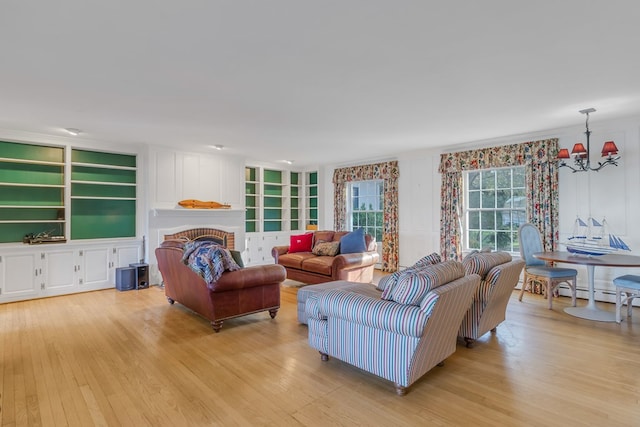 living room featuring built in shelves, light wood-type flooring, and an inviting chandelier