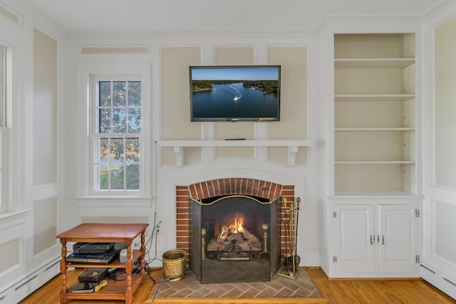 details featuring wood-type flooring, built in features, baseboard heating, and a brick fireplace