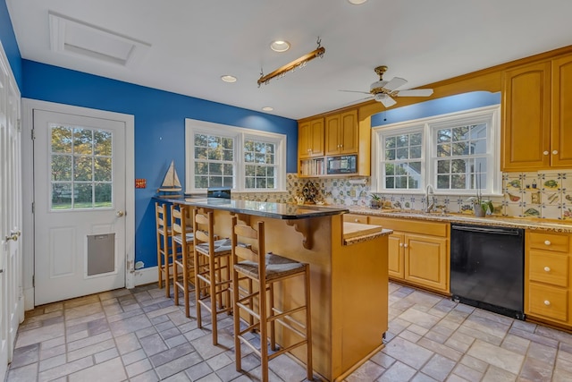 kitchen with ceiling fan, sink, tasteful backsplash, a breakfast bar area, and black appliances