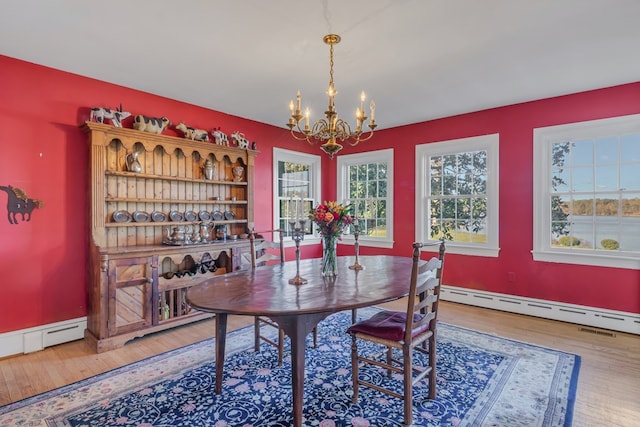 dining space featuring hardwood / wood-style floors, a baseboard heating unit, and an inviting chandelier