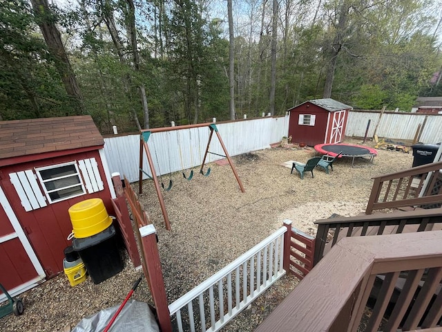view of jungle gym featuring an outbuilding, a fenced backyard, and a storage unit