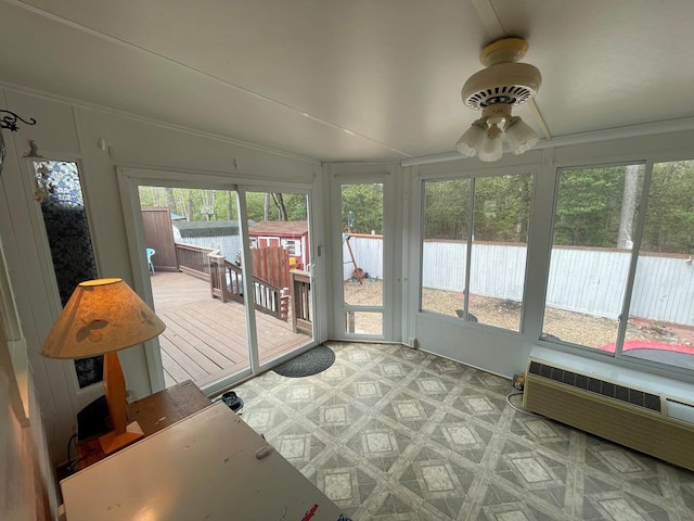 sunroom / solarium with radiator heating unit, a ceiling fan, and a wooden deck