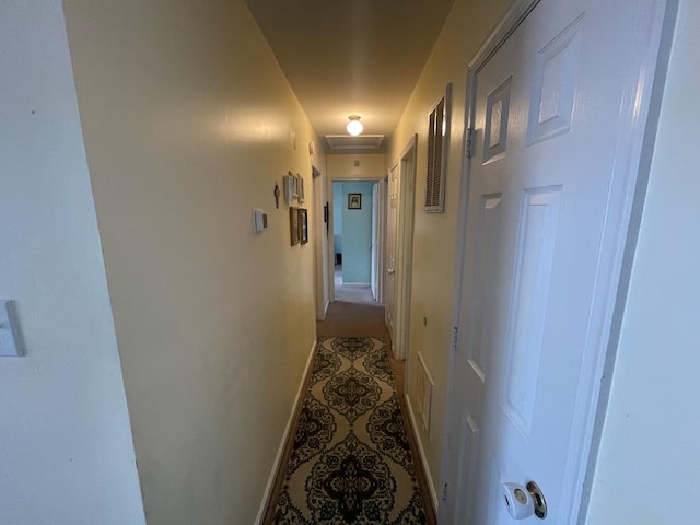hall featuring light tile patterned flooring, attic access, and baseboards