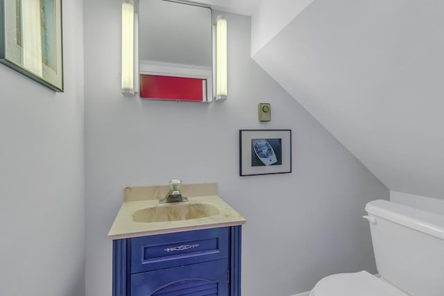 bathroom featuring vaulted ceiling, vanity, and toilet