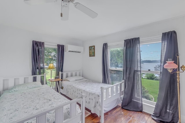 bedroom featuring an AC wall unit, multiple windows, ceiling fan, and hardwood / wood-style flooring