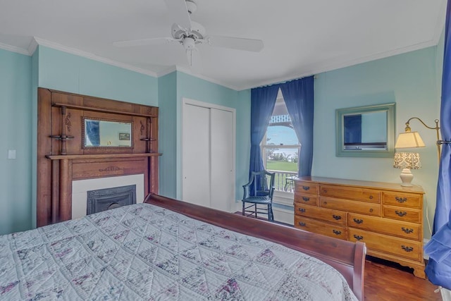 bedroom featuring a ceiling fan, ornamental molding, wood finished floors, a fireplace, and a closet