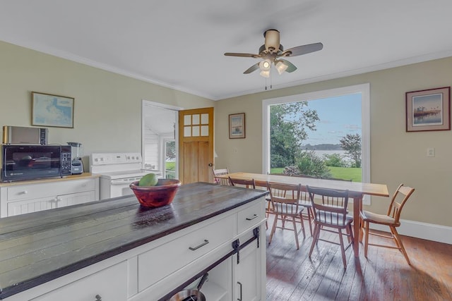 kitchen with white electric stove, dark countertops, ornamental molding, hardwood / wood-style floors, and white cabinetry