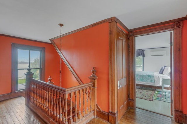 corridor with ornamental molding, hardwood / wood-style floors, and an upstairs landing