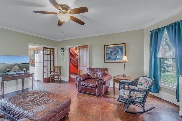 living area featuring crown molding, baseboards, and wood finished floors