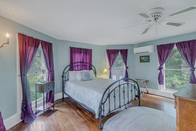 bedroom featuring an AC wall unit, ceiling fan, wood-type flooring, and baseboards