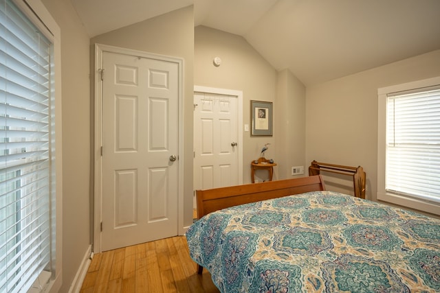 bedroom with light hardwood / wood-style flooring, multiple windows, and lofted ceiling