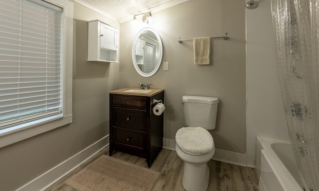 bathroom with vanity, toilet, ornamental molding, wood-type flooring, and a tub